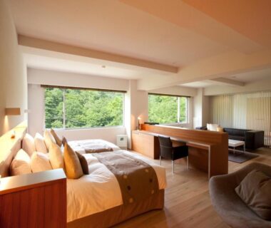 Twin beds and seating area overlooking verdant forest at Bourou NOGUCHI Noboribetsu, Hokkaidō ryokan room
