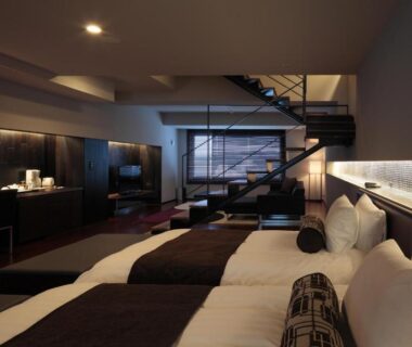 Contemporary multi-bed guest room with loft staircase, wood accents and seating at Bourou Noguchi Hakodate Hokkaidō