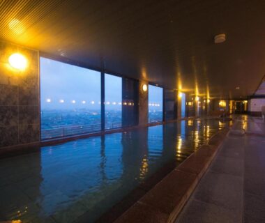 Indoor onsen with large windows at Bourou Noguchi Hakodate in Hokkaidō overlooking city lights