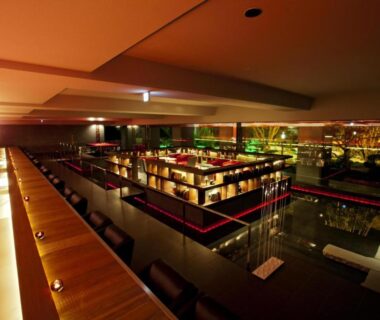 Low-lit modern interior with long wooden bar, central lounge seating and glass partitions at Bourou Noguchi Hakodate, Hokkaidō