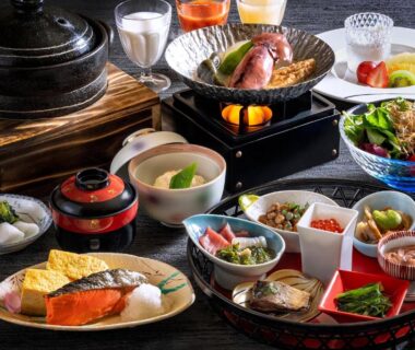 Assorted small dishes with grilled fish, tamagoyaki, miso soup and tabletop hot pot in a ryokan dining setting