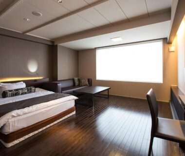 Wooden floored room with low table and bed at Bourou Noguchi Hakodate Hokkaidō