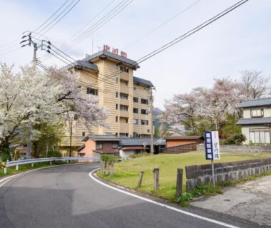 Exterior view of Bousenkaku with cherry trees along a curved road in Niigata