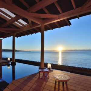 Wooden seaside onsen terrace with low stools and soaking pool at Bousui, Shizuoka, Japan