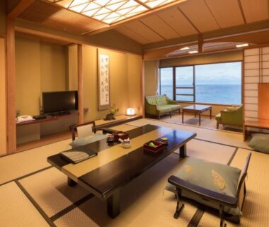 Traditional tatami room with low table, zabuton cushions, shoji screens and sea view at Bousui Shizuoka