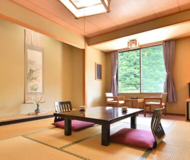 Traditional tatami room with low table, cushions, tokonoma alcove and garden view at Bouzantei Kotobuki Nagano