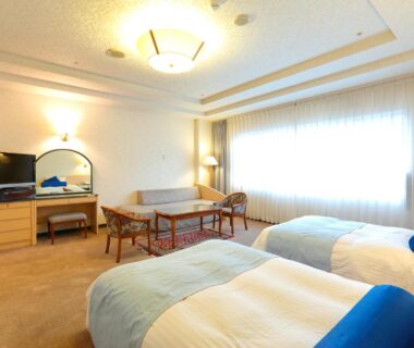 Spacious twin room with two beds, seating area, desk and large window at Boyokaku in Kumamoto, Kyūshū