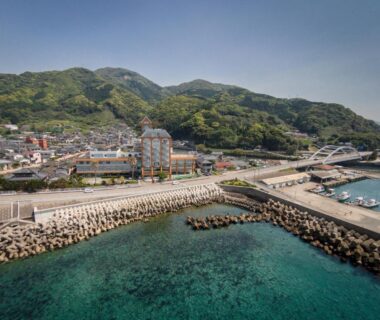 Clear turquoise harbor and breakwater near Boyokaku, small coastal town at the foot of green hills, Kumamoto Kyūshū