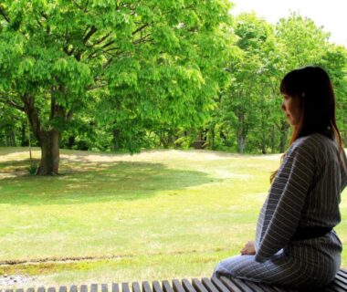 Person in yukata on engawa veranda overlooking green garden at Bunanoyado Koase, Niigata Chūbu
