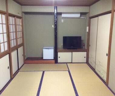 Traditional tatami room with shoji screens, low cabinet with TV and small refrigerator at Business Hotel Shizusato in Gifu