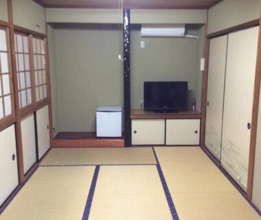 Tatami room with shoji screens, TV cabinet and small refrigerator at Business Hotel Shizusato, Gifu