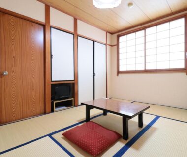 Traditional tatami room with low table and cushion, shoji screens and sliding doors at Business Ryokan Iroha Gifu