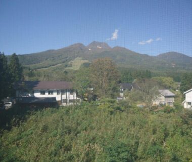 Grassy foreground, village houses and mountain backdrop at Cafe Cerisier栖里時絵 in Niigata
