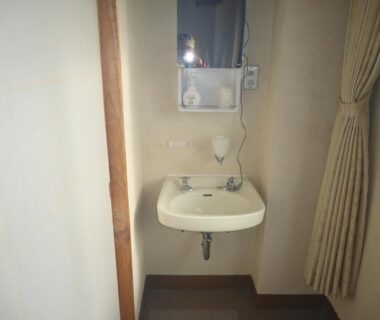 Wall-mounted sink with mirror and curtain in compact wash area at Cafe Cerisier栖里時絵 Niigata