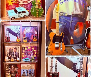 Wall-mounted and shelf guitars with music posters and miniature models in a display at Central Hotel, Nagano