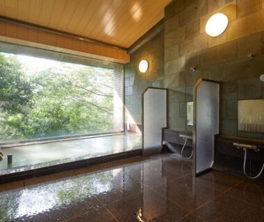 Indoor onsen bath with large window and shower stations at Centurion Hakone Bettei in Kanagawa, Japan