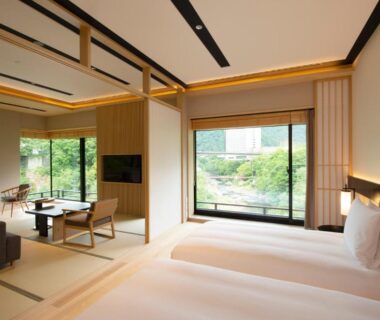 Bright tatami room with twin beds, low table seating and garden view at Chalet Ivy Jozankei in Hokkaidō Japan