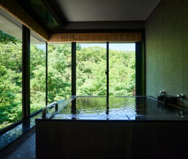 Wooden indoor soaking tub with floor-to-ceiling windows overlooking lush forest at Chalet Ivy Jozankei in Hokkaidō