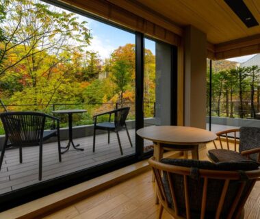 Wooden lounge and outdoor chairs on terrace overlooking autumn forest at Chalet Ivy Jozankei in Hokkaidō, Japan