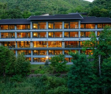Multi-story building with lit balconies among trees at dusk, Chalet Ivy Jozankei, Hokkaido
