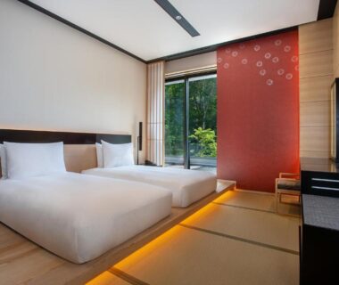 Twin beds on raised tatami platform with sliding glass door and garden view at Chalet Ivy Jozankei Hokkaidō