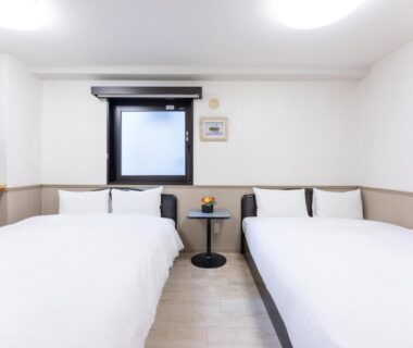 Two single beds with small round table at Chang Tee Hotel Ikebukuro Tokyo