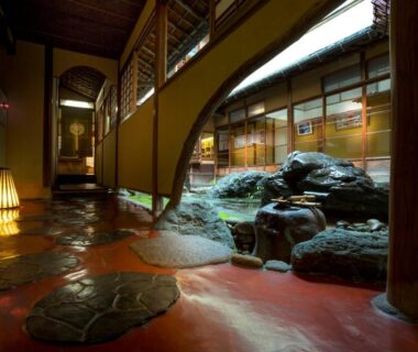 Stone walkway and lantern-lit indoor onsen garden with rocks and shoji screens at Charoku Bekkan Kyoto