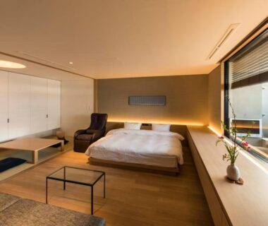 Spacious Japanese-style room with bed, tatami seating area, low table and large window at Chikurakan in Chiba
