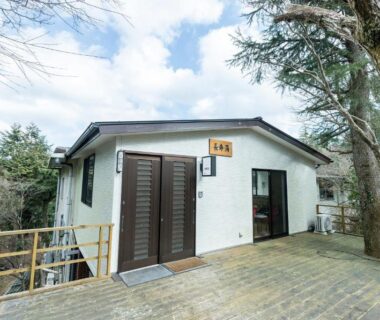 Wooden deck and exterior entrance of Chojuyu Hakone building surrounded by trees in Kanagawa