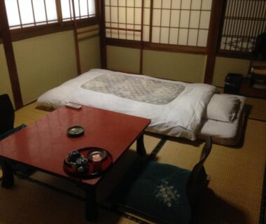 Traditional tatami room with futon, low table and shoji screens at Chuokan Shimizuya Ryokan in Nagano Japan
