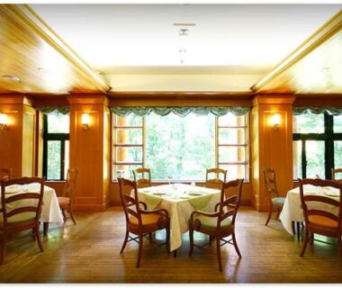 Bright ryokan dining room with round tables and wooden chairs at Chuzenji Kanaya Hotel in Tochigi