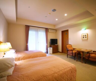 Spacious twin room with two beds, seating area, TV and curtains at Chuzenji Kanaya Hotel Tochigi