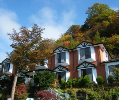 Hillside gabled cottages at Chuzenji Pension in Tochigi, Japan surrounded by trees and shrubs