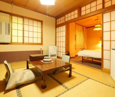Traditional tatami room with low table, cushions and bed behind shoji screens at Dai Onsen Matsudaya Ryokan in Iwate