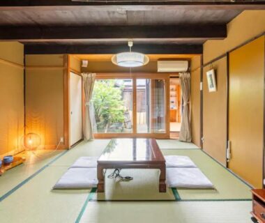 Tatami room with low table, zabuton cushions and shoji doors opening to a garden courtyard at Daitokuji Sushicho, Kyoto