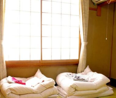 Traditional tatami room with folded futons and shoji window at Daiya Ryokan, Kyoto, Kansai