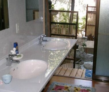 Double sink vanity leading to wooden step and stone bathing area behind bamboo screen at Daiya Ryokan, Kyoto