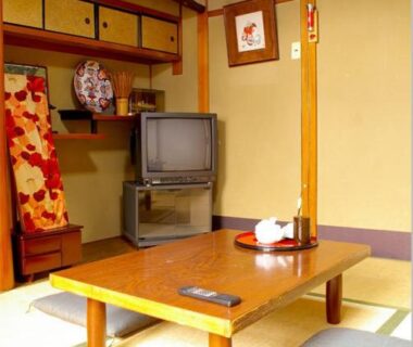 Tatami room with low table, TV, kimono and display shelf at Daiya Ryokan Kyoto