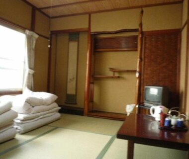 Tatami room with stacked futons, low table and tea set at Daiya Ryokan in Kyoto