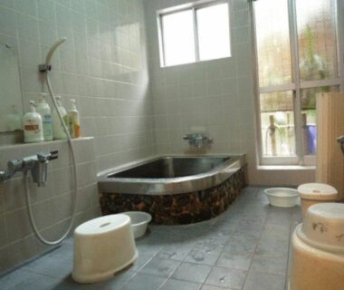 Tiled bathing room with soaking tub, wash stools and handheld showers