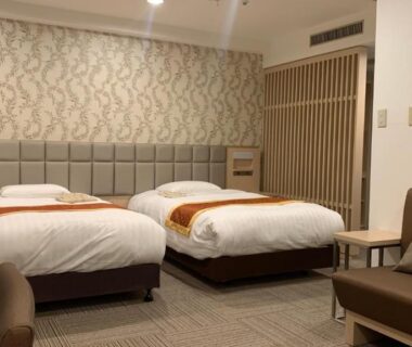 Spacious twin beds with sofa seating, patterned wallpaper and bedside controls in Day Nice Hotel Tokyo room