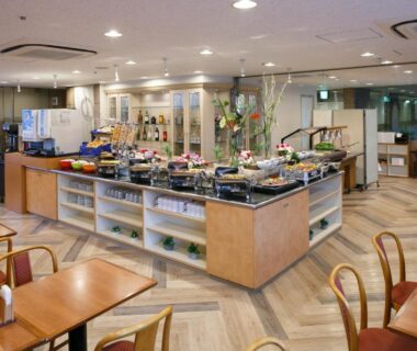 Buffet dining area with central food counters and wooden tables at Day Nice Hotel, Tokyo