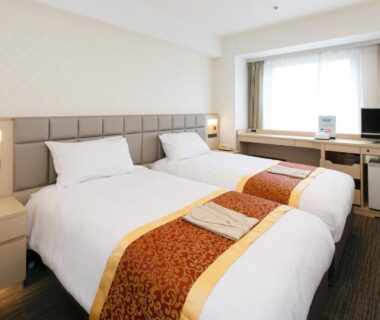 Twin beds with bedside lamps, desk, TV and curtains at Day Nice Hotel Tokyo