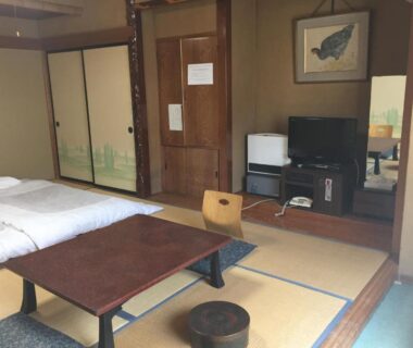Traditional tatami room with futon, low table and sliding fusuma doors at Daymaruya Ryokan in Nagano, Chūbu