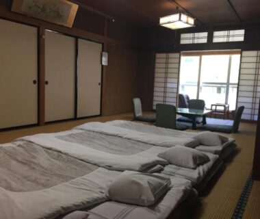 Tatami room with futons, low table and shoji screens at Daymaruya Ryokan in Nagano