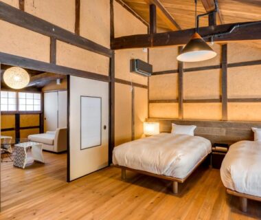 Spacious room with twin beds, exposed wooden beams, shoji screens and seating area at EN Takeda Castle Town Hotel Hyōgo