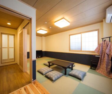 Tatami room with low table, zabuton cushions and kimono stand at Ebisu Ryokan in Kyoto
