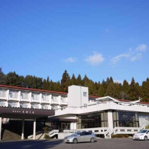 Multi-story ryokan building with parked cars and forested hillside, Eboshiso, Iwate Tōhoku