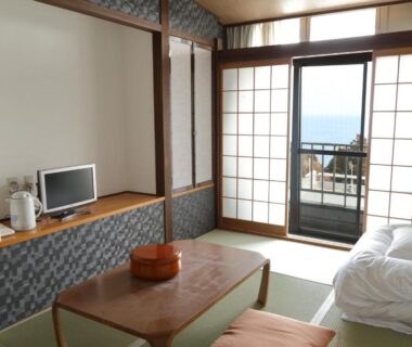 Tatami room with futon, low table and shoji doors opening to balcony at Eboshiso in Iwate