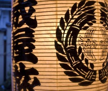 Glowing paper lantern with black kanji and crest hanging outside Ekinariya Ryokan in Gunma Kanto